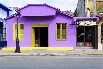 San Juan del Sur, Nicaragua, A vibrant purple house with yellow shutters and a colourful surfboard