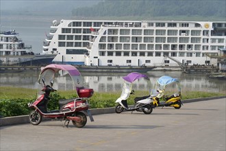 Chongqing, Chongqing Province, scooter with canopy on a riverside promenade, a cruise ship in the