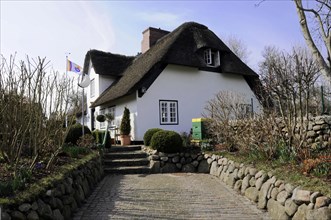 Sylt, North Frisian Island, Schleswig Holstein, White thatched house with a stone path surrounded