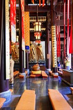 Jade Buddha Temple, Shanghai, Interior view of a temple with statues, wooden benches and red