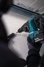 A person working with a Makita drilling machine on the ground, solar systems construction, trade,