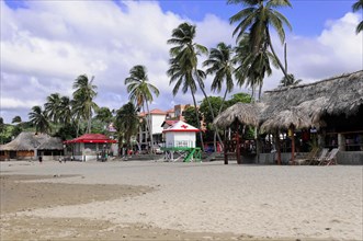 San Juan del Sur, Nicaragua, beach with palm trees and huts, cloudy sky, tropical tourism sign,