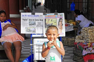 Granada, Nicaragua, Happy child presents newspaper headlines while selling on the street, Central