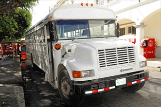 Leon, Nicaragua, White school bus parked on the roadside under trees in an urban area, Central