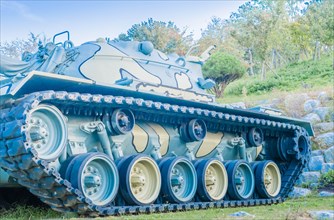 Side view of army tank in camouflage paint on display in public military history park on sunny