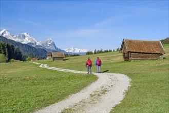 Two hikers at Geroldsee or Wagenbruechsee, Estergebirge with huts, Kruen near Mittenwald,
