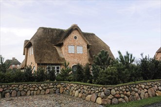 Sylt, North Frisian Island, Schleswig Holstein, A large thatched house behind a stone wall on an