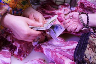 Chongqing, Chongqing Province, China, Two people exchange money for meat at a colourful