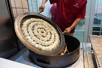Stroll in Chongqing, Chongqing Province, China, Asia, A cook prepares dumplings in a large pan over