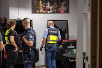 Financial control officers discuss in an office next to a painting, The Cologne police led a raid