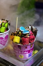 Ice cream sundae with cake on a market stall, sweets, sugar, unhealthy, colourful, gaudy,