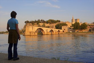 Woman on the banks of the Rhone looking towards the Pont Saint Benezet bridge, the Papal Palace and