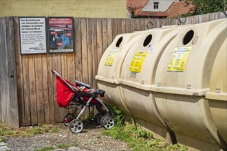 Pushchair left in front of a recycling container in the old town centre of Memmingen, Swabia,