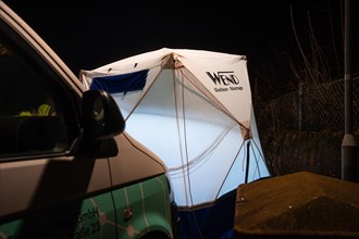 Night work scene with illuminated emergency tent and a visible emergency vehicle, Galsfaserbau,