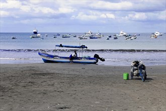 San Juan del Sur, Nicaragua, A fisherman on the beach prepares his boat, a bicycle stands in the