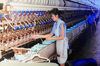 Silk factory Shanghai, A worker operates weaving machines with bobbins of silk threads, Shanghai,
