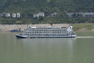 Cruise ship on the Yangtze River, A large white cruise ship is anchored in the river near green