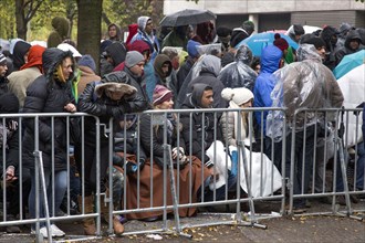 Syrian refugees wait for their registration in cold and wet weather at the Berlin State Office for