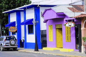 San Juan del Sur, Nicaragua, Cheerful, colourful facades of houses in a street with a parked car in