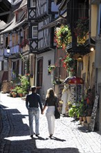 Eguisheim, Alsace, France, Europe, A couple walks hand in hand through a picturesque alley with