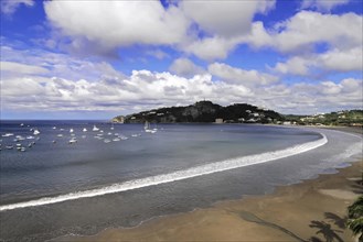 San Juan del Sur, Nicaragua, A peaceful bay with a beach and yachts nestled in a green coastline,
