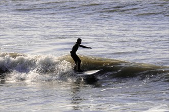 Westerland, Sylt, Schleswig-Holstein, Germany, Europe, Surfer riding a wave in the sea, surrounded