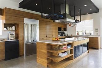 Kitchen with American walnut wood island, cabinets and quartzite countertops inside modern cube