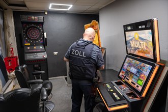 A customs officer checks a slot machine in a dark room, The Cologne police led a raid against