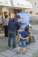 Artist with young spectator in Alghero old town, Sassari province, Sardinia, Italy, Mediterranean,