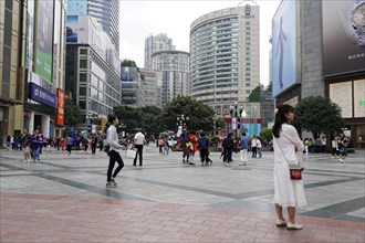 Chongqing, Chongqing Province, China, Asia, People walking across a square in front of modern