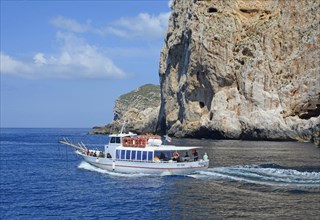 Excursion boat at the rocky coast of Capo Caccia, Alghero, Sassari Province, Sardinia, Italy,
