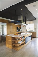 Kitchen with American walnut wood island, cabinets and quartzite countertops inside modern cube
