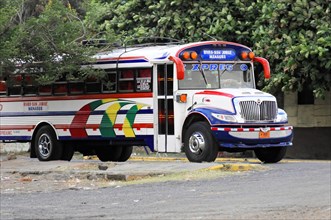 On the road near Rivas, Ometepe Island, Nicaragua, Parked colourful city bus surrounded by trees on