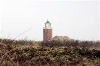 Lighthouse of Kampen, Small brick lighthouse stands between dunes under a cloudy sky, Sylt, North