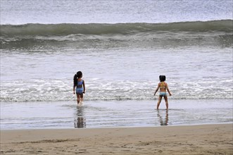 San Juan del Sur, Nicaragua, Two children playing on the beach near the water under a cloudy sky,