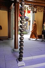 Jade Buddha Temple, Shanghai, Monk walking past ornate temple pillars and traditional carvings,