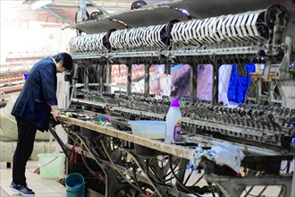 Silk factory Shanghai, A worker cleans and maintains a machine in a textile factory, Shanghai,