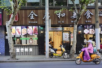 Shanghai, China, Asia, A busy street scene with a restaurant, a scooter and people passing by,