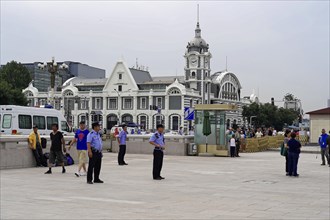 Beijing, China, Asia, City square with people walking and a historical building with clock tower in