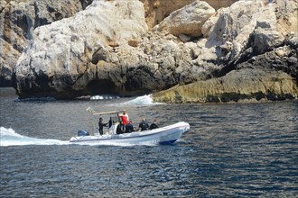 Speedboat with divers at the rocky coast of Capo Caccia, Alghero, Sassari Province, Sardinia,