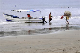 San Juan del Sur, Nicaragua, Fishermen on the beach hauling in fishing nets next to a boat, Central