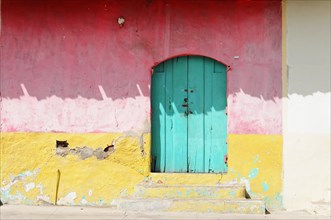 Granada, Nicaragua, A striking turquoise door embedded in a red, peeling wall, Central America,