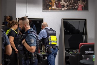 Customs officers talking inside a gaming room with surveillance monitors, The Cologne police led a