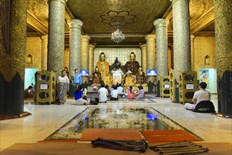 Shwedagon Pagoda, Yangon, Myanmar, Asia, Believers meditate in front of golden Buddha statues in a