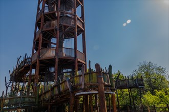 Wooden observation tower with winding staircase on top of mountain on sunny day with blue sky in