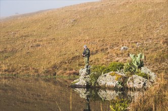 Sport fisherman fishing in lake on cloudy day, Cambara do sul, Rio Grande do sul, Brazil, South