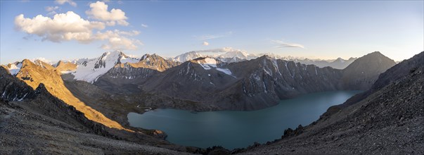 Panorama, turquoise mountain lake Ala Kul Lake, mountain peaks with glaciers glow red at sunset,