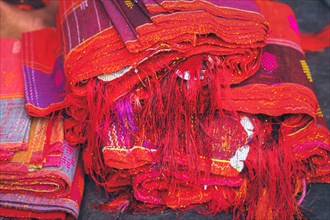Close up to a stack of vibrant red Ulos fabric showcasing indigenous ethnic design showing the