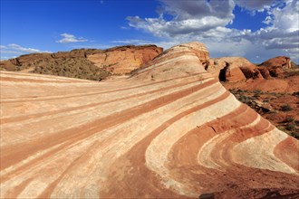Picture shows an impressive desert landscape with undulating red rocks under a blue sky, Valley of