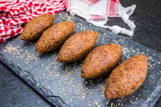 Delicious Lebanese (Arabic) food, kibbeh (kibe) on black slate stone and granite background with